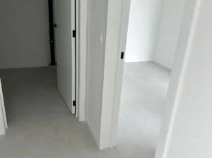 Close-up van twee openstaande deuren in een modern interieur, met strakke witte muren en een lichtgrijze tegelvloer. Minimalistisch.