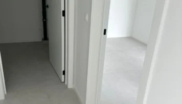 Close-up van twee openstaande deuren in een modern interieur, met strakke witte muren en een lichtgrijze tegelvloer. Minimalistisch.