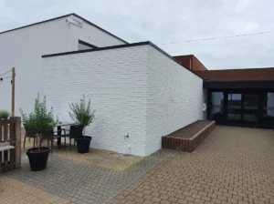 Recent gerenoveerde witte bakstenen gevel met strakke afwerking en een patio met grijze en bruine bestrating