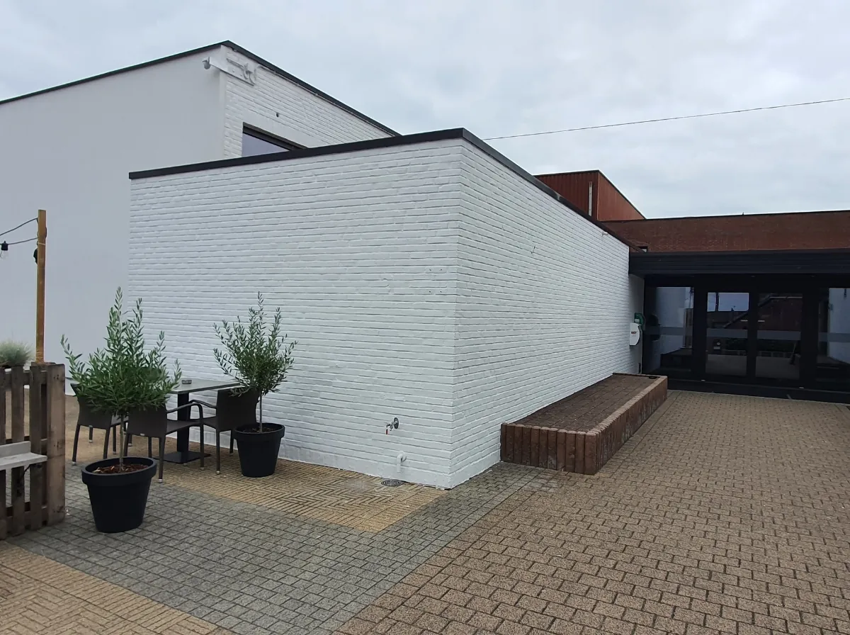 Recent gerenoveerde witte bakstenen gevel met strakke afwerking en een patio met grijze en bruine bestrating