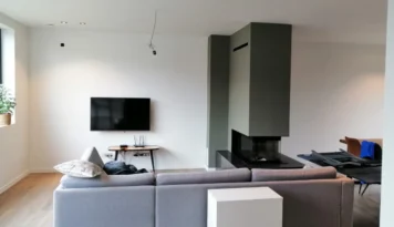 Geverfde haard en witte muren in moderne woonkamer met bank en televisie in Limburg.
